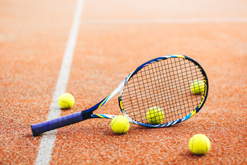 tennis racket with many balls on clay court..