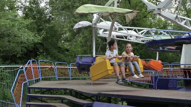 Two children ride on the carousel in an amusement park