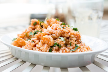 Tasty risotto with Shrimp, fresh herbs vegetables on a white pla