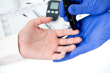 Pricking a finger with lancet to measure blood glucose amount.