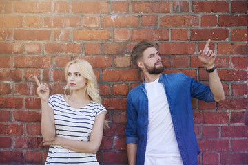 Obraz na płótnie Canvas Young couple pointing on the brick wall