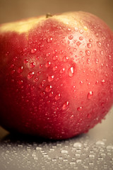 Apple with drops of water on a wet surface. Shallow depth of fie