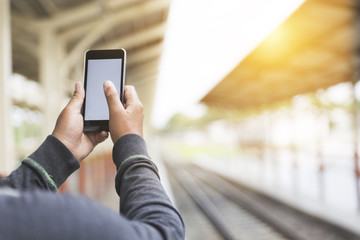 man holding smartphone at train station