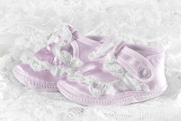 Pink baby booties on a lace background