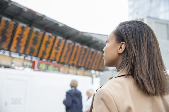Female Commuter Looks At Departure Boards In Railway Station