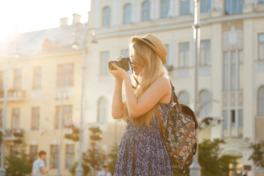 Outdoor summer smiling lifestyle portrait of pretty young woman having fun in the city in Europe in evening with camera