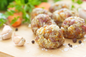 Raw meatballs on a chopping board and ingredients