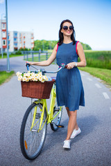 happy woman in dress posing with vintage bicycle with basket