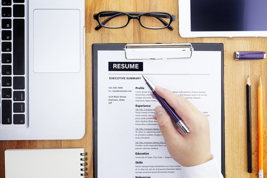 Businessman or HR Manager review a resume on his desk with Magnifier, computer laptop, digital tablet, calculator and glasses. Resume information with magnifier. Flat lay.