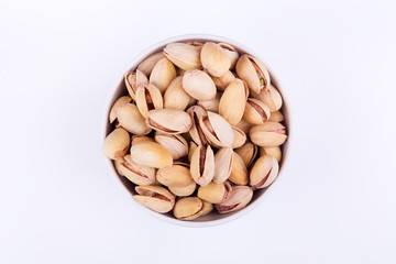 Salted pistachios in a bowl on white background. Top view with copyspace