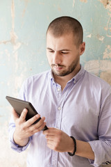 Young man with tablet by the wall