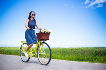 travel concept - happy woman riding retro bicycle in countryside