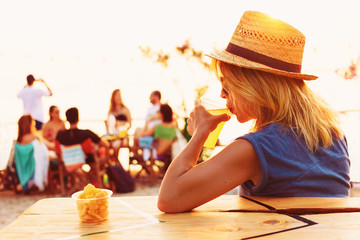 Young woman drinking beer in a beach bar