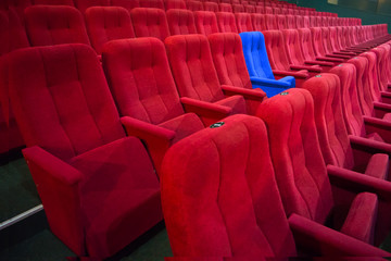 Blue chair between rows of red seats