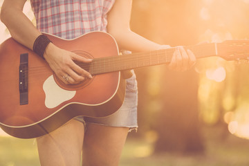Close up of female hands playing acoustic guitar in nature. Retro, music, lifestyle concepts.