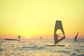Transparent silhouettes double exposure of wind surfers on sea at the sunset. Sport, summer and vacation concepts.