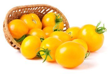 yellow tomatoes spilled from a wicker basket isolated on white background
