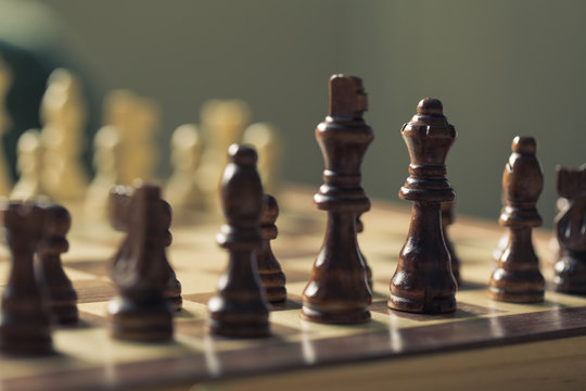 Black chess pieces in brown against white ones.