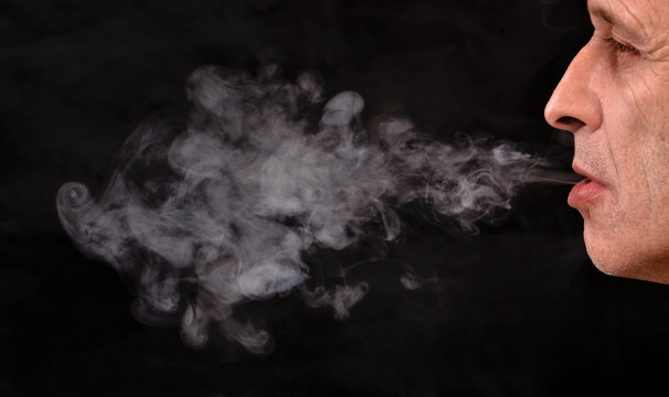 Retrato de la cara de un hombre fumando en fondo blanco.