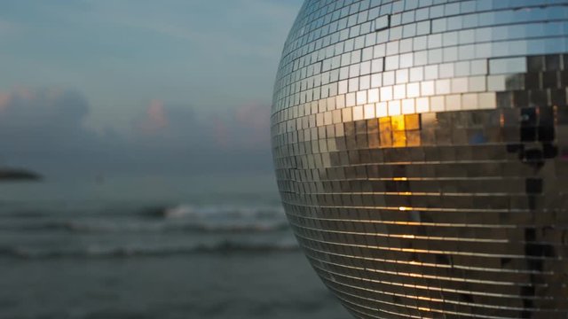 discoball spins during sunrise on the beach