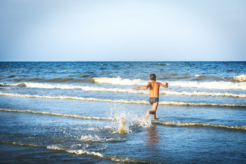 Fototapeta na wymiar Boy running on the waves