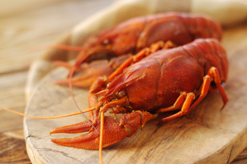 Boiled crawfishes on a wooden board on a wooden background, close up