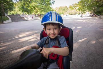 Little boy smiling in the seat bicycle. Kid has biking helmet. Protection on the bicycle.