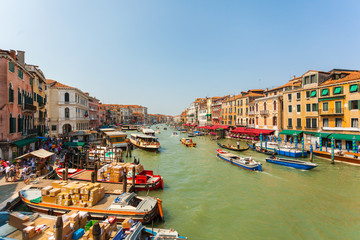 Grand Canal in Venice in the afternoon with a lot of gondolas, boats, ferries, etc. Brightly colored houses and Palazzo of Venice with facades in different styles. Italy