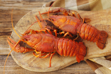 Boiled crawfishes on a wooden board on a wooden background, close up