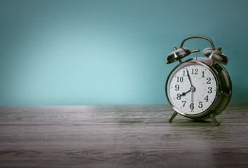 Retro alarm Clock on wood table blue Background