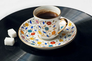 Cup of black coffee on surface of music vinil plate. Sound of morning.