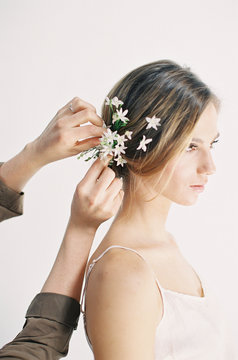 Hairdresser placing floral arrangement in woman's hair