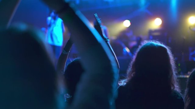 people waving hands at live concert, blue light