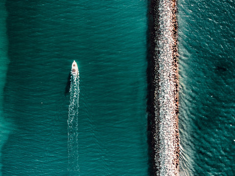 Boat passing by sea wall, view from above