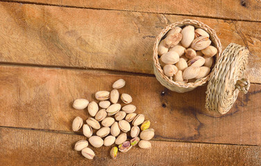 Roasted and salted pistachios in a basket and on a rustic table top view
