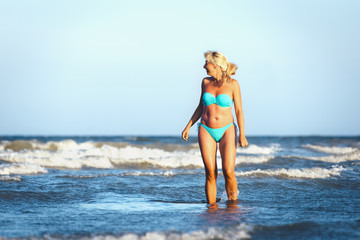 Fototapeta na wymiar The girl in a swimsuit walking on the waves