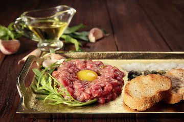 Steak tartar with chopped onion and pickles on a tray