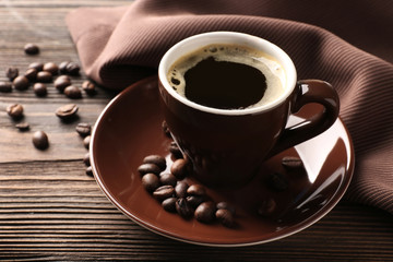 Cup of coffee with beans on wooden table