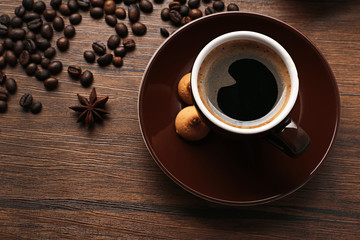 Cup of coffee with beans on wooden table