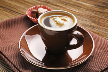 Cup of coffee with candies on napkin