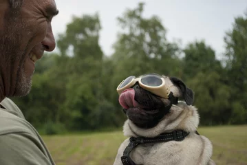 Fototapeten Volwassen man met hondje dat een hondenbril draagt © monicaclick