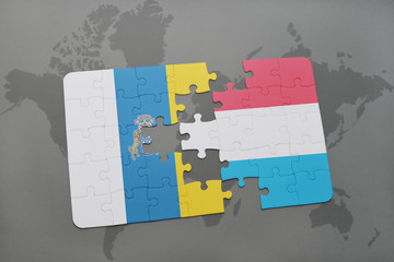 puzzle with the national flag of canary islands and luxembourg on a world map background.