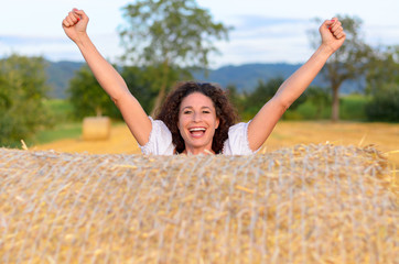 Excited young woman celebrating in a farm field