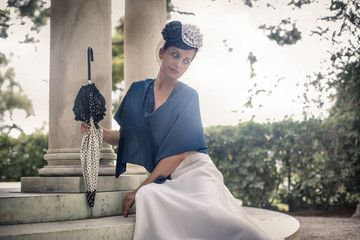 Elegant woman dressing vintage costume posing sitting in a beautiful garden