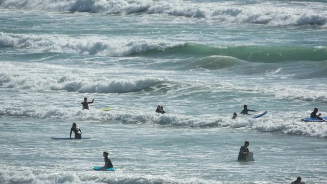 beach full of surfers in cornwall england