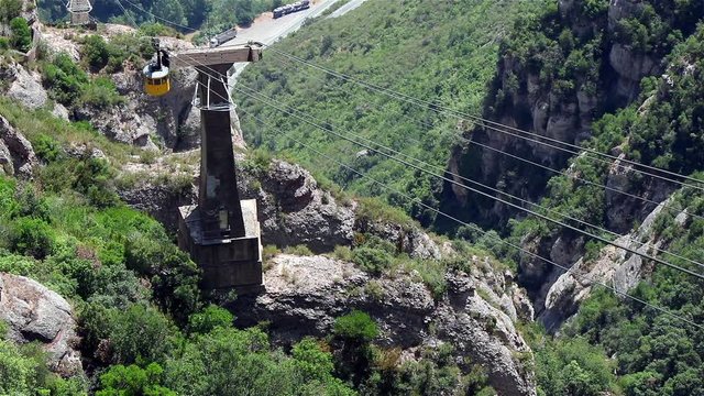 A top view of a yellow cable way car going up on the Montserrat mountain near Barcelona, Spain, July 2016