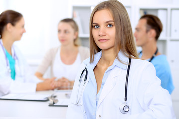Fototapeta premium Happy doctor woman with medical staff at the hospital sitting at the table and discussing medical history