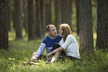 Fototapeta premium Young couple sitting in the grass near the tree in the Park . Honeymoon.