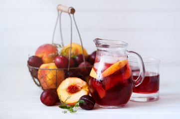 Iced fruit compote with peaches and plums. Cold summer drink.