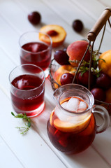 Iced fruit compote with peaches and plums. Cold summer drink.